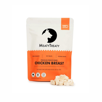 A stand-up pouch of MeatyTreaty Premium Freeze Dried Chicken Breast pet treats, shown on a white background with several light beige freeze-dried treat cubes in front of the package.