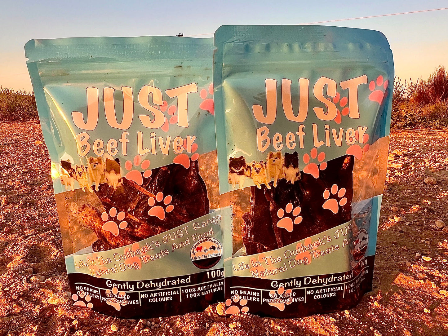 Two packages of 'Just Beef Liver' pet food on a dirt road.